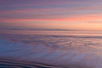 Obraz premium Soft pastel colors of ocean waves of the Pacific Ocean, as the sun sets over the Monterey Bay, Santa Cruz, California 