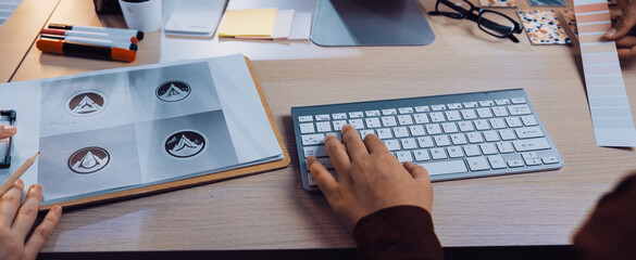 A vibrant creative workspace featuring a computer, design tools, color swatches, and hands of designers collaborating on a branding project, showcasing creativity and innovation. SACTR