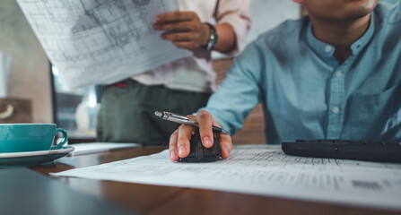 Engineers or architects working together on building plans, reviewing blueprints and using digital tools, representing technical design, project planning, collaboration, and construction workflow.