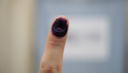 A close up of a person's finger with purple election ink after casting their vote
