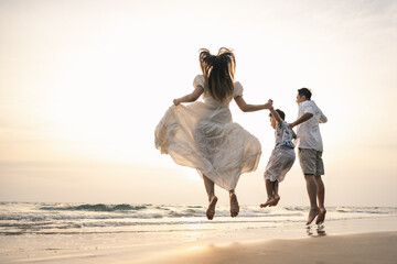 A joyful family jumping together on the beach during sunset, representing happiness, bonding, leisure travel, and the warm, relaxing atmosphere of a summer vacation by the sea.