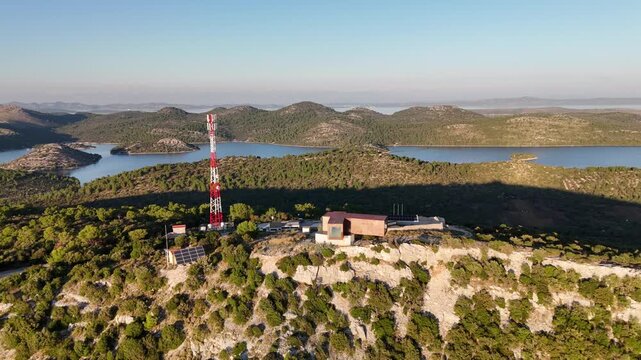 A cinematic drone journey over Telascica cliffs and tourist center at sunset, flying backwards to reveal the island, cove, and coastline bathed in warm golden light.