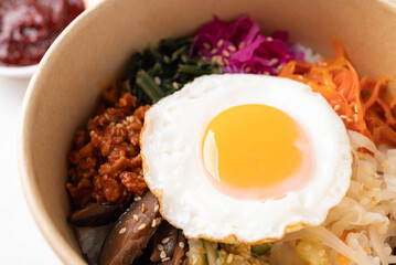 Bibimbap, Korean food, Cooked rice with vegetables, pork and egg in biodegrable bowl