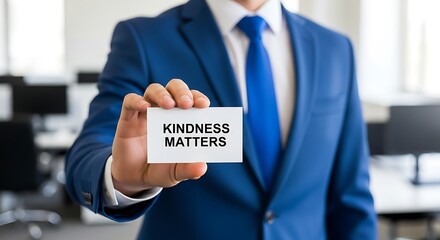 Businessman in blue suit holds card emphasizing kindness matters in office setting