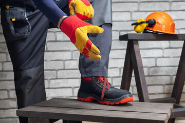 Construction worker putting on the gloves and hard hat preparing for work.