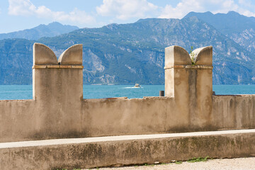 Blick von Malcesine &uuml;ber die Mauer des Kapit&auml;nspalastes auf den Gardasee mit den Bergen der Lombardei in Italien