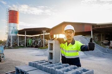 A construction workers wearing protective clothing carefully inspect stacking hollow concrete blocks (concrete blocks) in an indoor factory or construction material storage area.