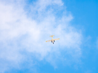Small ultralight airplane with overhead wing and single propeller flying in sunset sky.