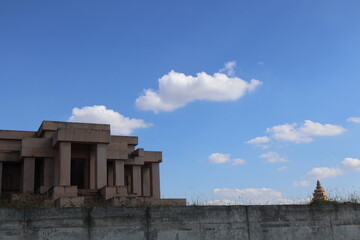 An ancient temple nestled within a fortified enclosure under a partly cloudy sky. The temple,...