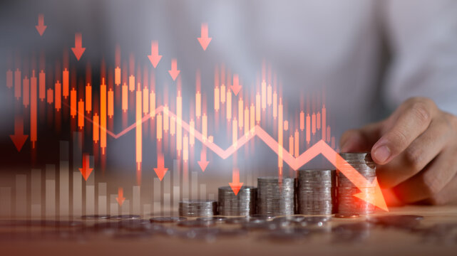 Stacks of coins falling value alongside red downward financial chart, symbolizing bankruptcy, economic decline, investment loss, financial instability during market downturns ,recession-driven crises