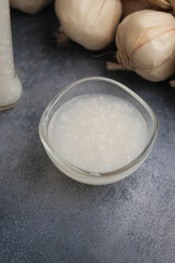 garlic sauce in a bowl beside garlic on a kitchen counter