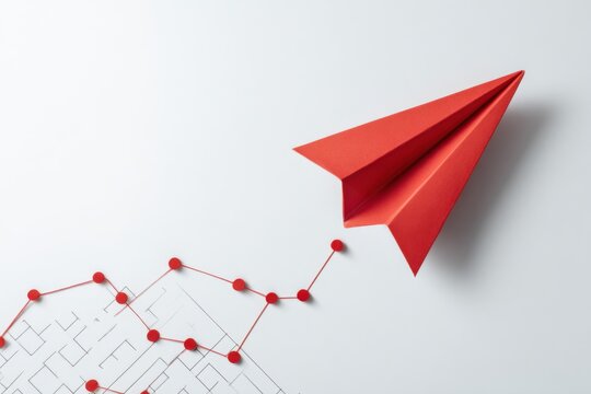 Red paper plane soaring above a strategy chart on a clean white surface, symbolizing innovative business planning and creative ideas in a competitive environment