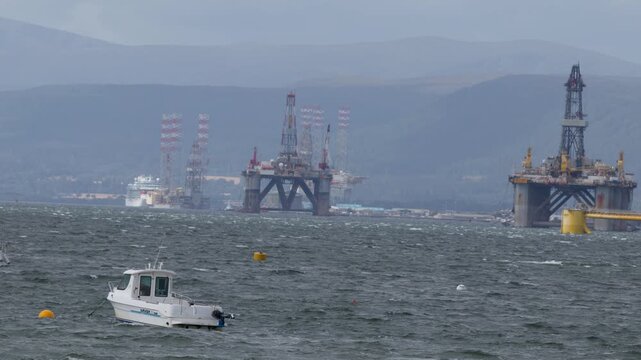 Small Boat Passes Offshore Oil Rigs in Windy Cromarty Firth