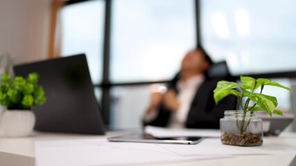Businessman Relaxing in Modern Office with Green Desk Plant