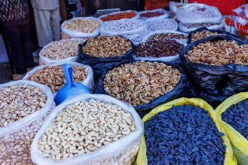 Vibrant marketplace display of assorted dried fruits, nuts, and seeds from local vendors in an open market bustling