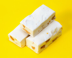 White nougat pastille candies with nuts. Sweet confectionery on a yellow background