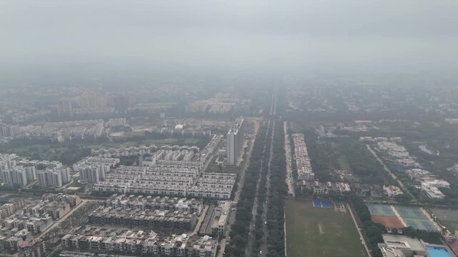 The drone viewpoint captures Greater Noida&rsquo;s organized neighborhoods and lush green road dividers.