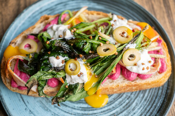 Breakfast served. Delicious bruschetta. Healthy veggie toast with beetroot food. Runny creamy sauce with grilled greens herbs on bread.