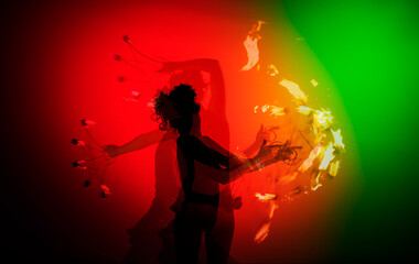 Fire dancer performs with in front of a red green background
