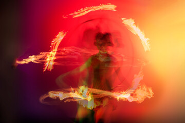 Fire dancer performs with in front of a red green background

