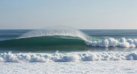 Obraz premium Powerful ocean wave cresting. A massive, turquoise wave explodes in a dramatic crest, with frothy white spray. Calm, light-blue sky above