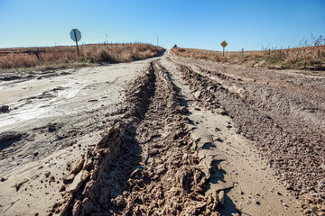 Naklejka premium Western rural dirt road in Kansas with tire tracks, erosion and ruts from rain water