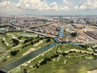 Scenic aerial view showcasing lush golf courses and urban landscape during flight to Singapore