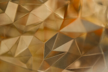 abstract golden geometric background. the texture resembles cut glass, crystal, or a diamond surface, perfect for luxury, technology, and futuristic designs.