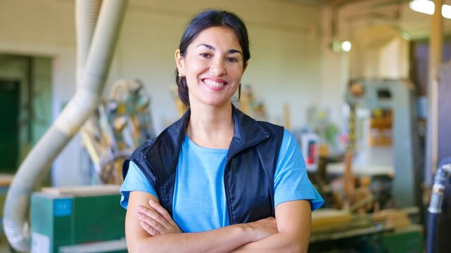 Confident female artisan smiling in woodworking workshop