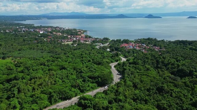 A forward elevated aerial of the winding road leading to Talisay town on the edge of Taal Lake in Batangas, Philippines