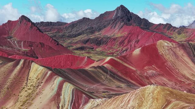 Rainbow Mountain Vinicunca Peru Per&uacute; aerial drone morning blue sky Monta&ntilde;a de Siete Colores Palccoyo clouds Peruvian Andes Red Valley striped hills seven colored Cusco Region parallax backwards pan up