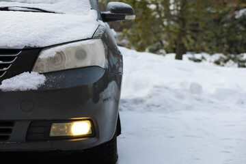 Car with Snow-Covered Headlights and Winter Landscape Background