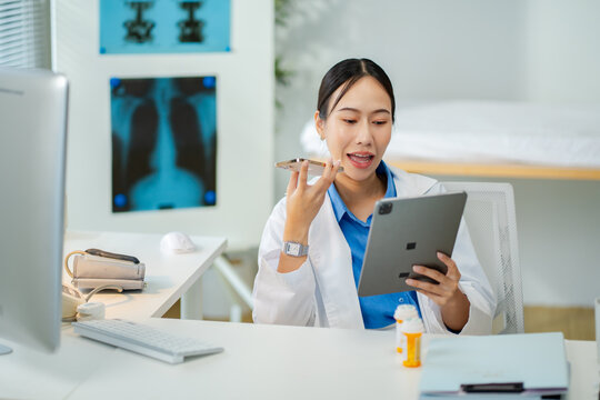 Asian female doctor consultation or tell patients the results of examinations by mobile phone and holding tablet at clinic hospital.Concept of telemedicine,remote consultation and modern healthcare