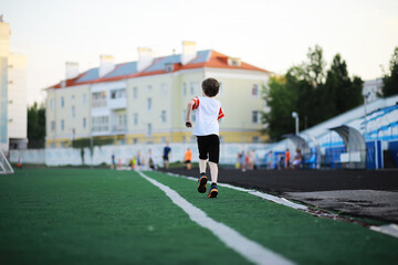 The child goes in for sports at the stadium. The boy is training before playing football.