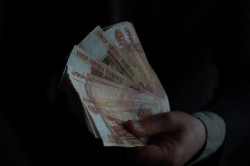 a man in an expensive suit holds a lot of money in his hand, Russian rubles, bills of five thousand...