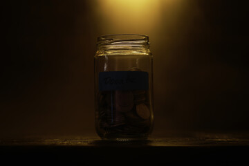 Dimly Lit Donation Jar Filled with Coins, Symbolizing Charity and Generosity in a Warm Atmosphere