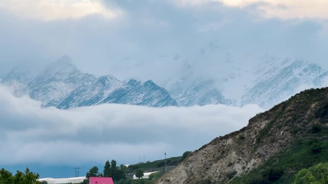 4K Landscape shot of clouds under the snowy Himalayan mountain range during the winter season after a storm as seen from Gondhla village in Lahaul and Spiti district, Himachal Pradesh, India. 