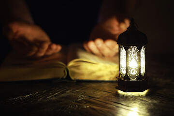 Ornamental Arabic lantern with burning candle glowing at night. Festive greeting card, invitation...