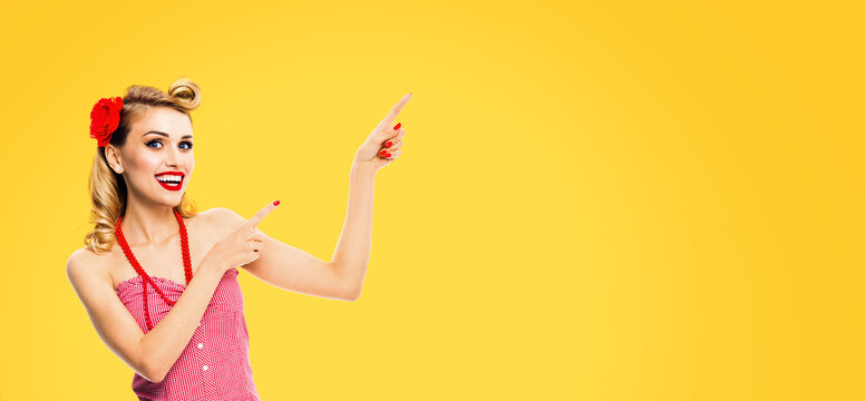Banner image - happy cute woman pointing finger, advertise. Expressive smile blonde girl in pinup cloth, show free text space. Retro fashion vintage ad concept. Isolated yellow background