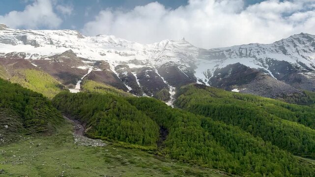 4K Landscape shot of scenic Himalayan mountain range with clouds above it as seen from Sural Bhatori in Pangi Valley, Chamba district, Himachal Pradesh, India. Scenic view of snowy Himalayas in India.