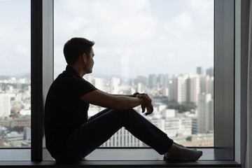 Man Sitting Alone by Window Looking Out at City Skyline, Contemplative Mood