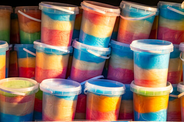 Colorful layered cotton candy in plastic cups arranged on a stall, creating a vibrant sweets display during an outdoor event