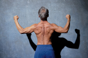 Obraz premium ポーズをとる筋肉のあるシニアの男性 後ろ姿