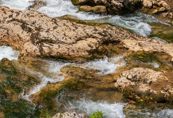 a narrow canyon of a mountain river in the embrace of a granite monolith with vegetation along the banks