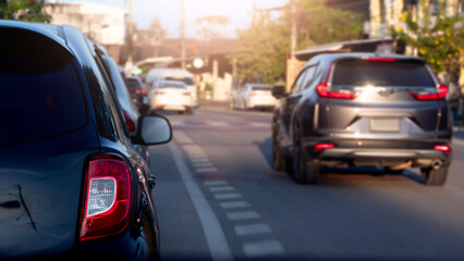 Rear side view luxury of black car. with other cars drive over to the side. Front side of car with sunlight and blurred of trees and town. at day time.
