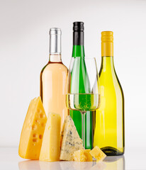 Naklejka premium Assorted cheeses and wine bottles on white background
