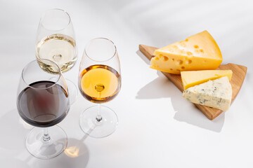 Naklejka premium Assorted cheeses and wine glasses on white background
