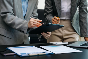 Business documents on office table with smart phone and calculator digital tablet and graph business with social network diagram and two colleagues discussing data