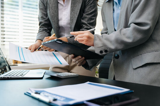 Business documents on office table with smart phone and calculator digital tablet and graph business with social network diagram and two colleagues discussing data