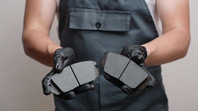 Close-up of mechanic touching high-quality, rough brake pads on car, showing in black-gloved hands. Concepts for auto parts replacement, car maintenance, brake system health, high-quality auto parts